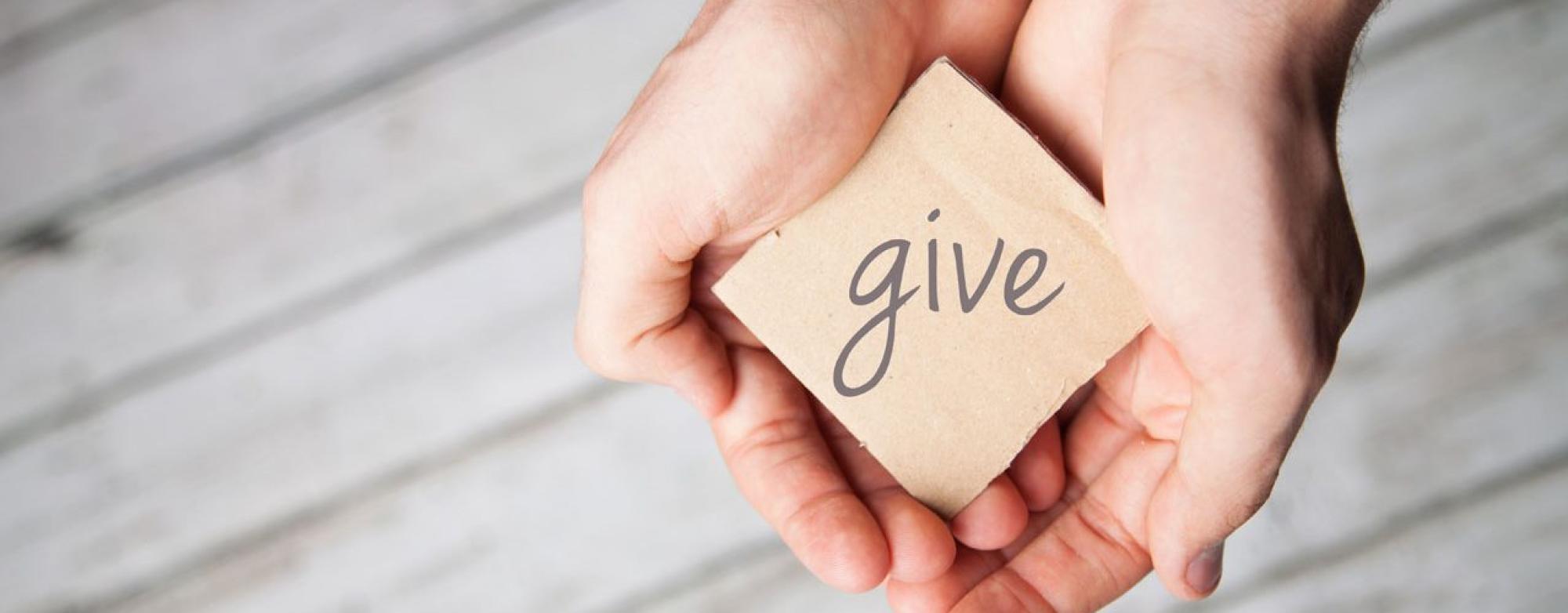 Hands holding a ‘GIVE’ sign symbolising support for MS Ireland