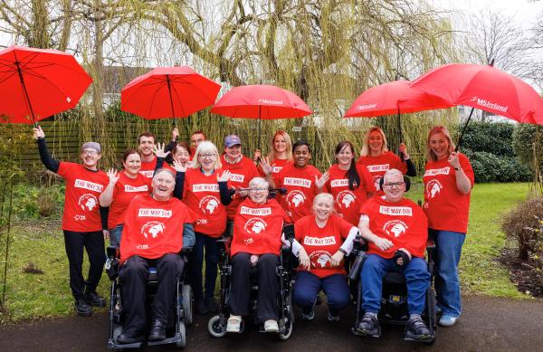 Group of people in red t-shirt holding red umbrellas 