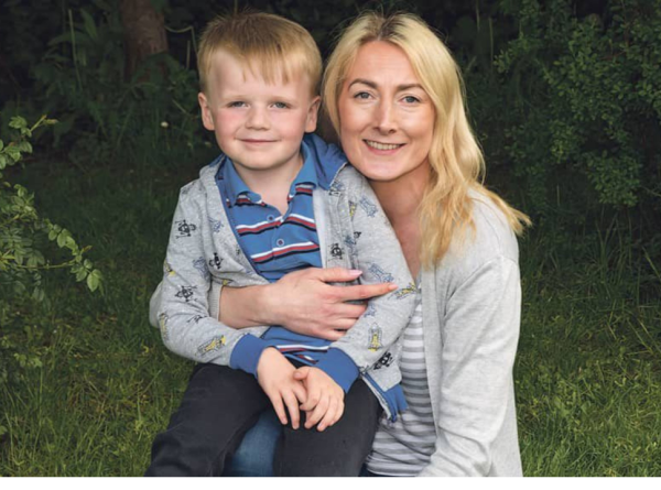 Naomi and her son sitting together, smiling warmly with a garden backdrop