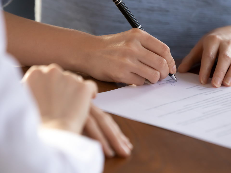 two people at a desk and one of them signing a document