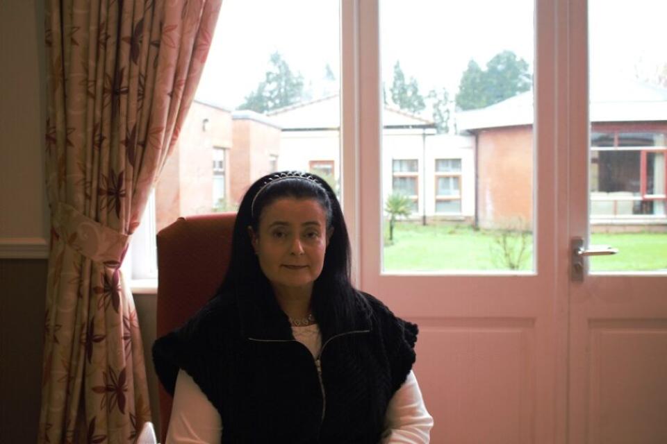 Person sitting in chair beside a pink glass 