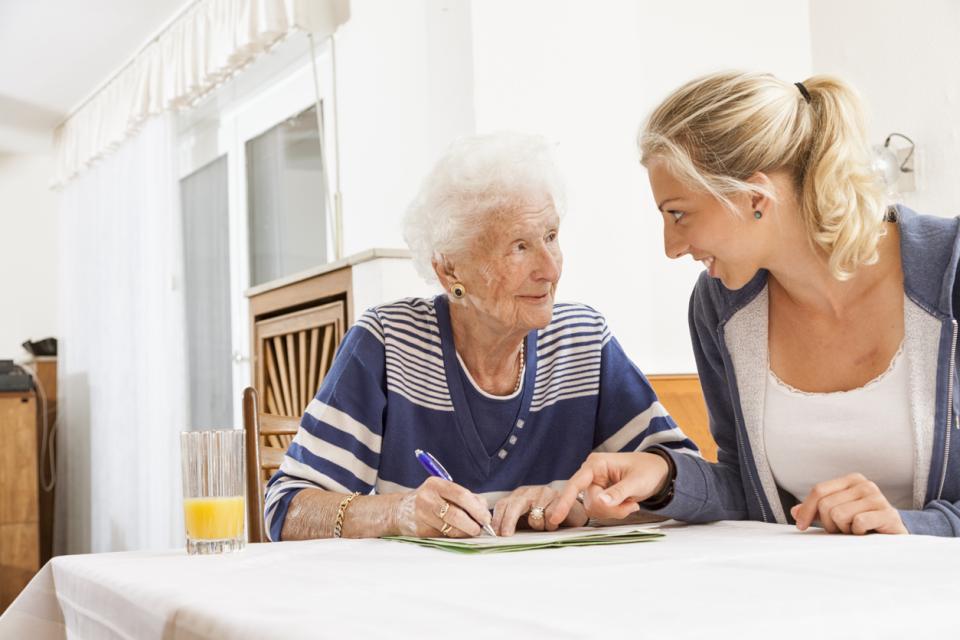 Two people are seated at a table. One of them is holding a pen