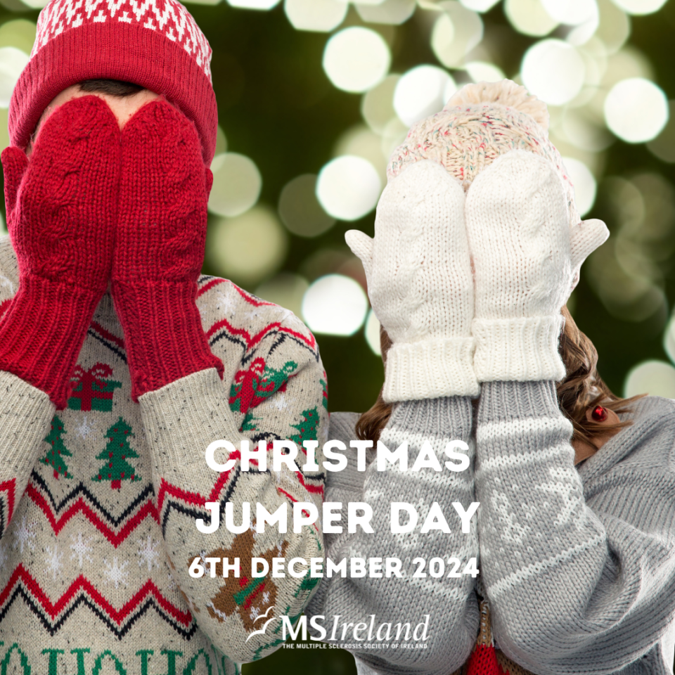 Two individuals standing, covering their faces with gloves, both wearing festive Christmas jumpers.