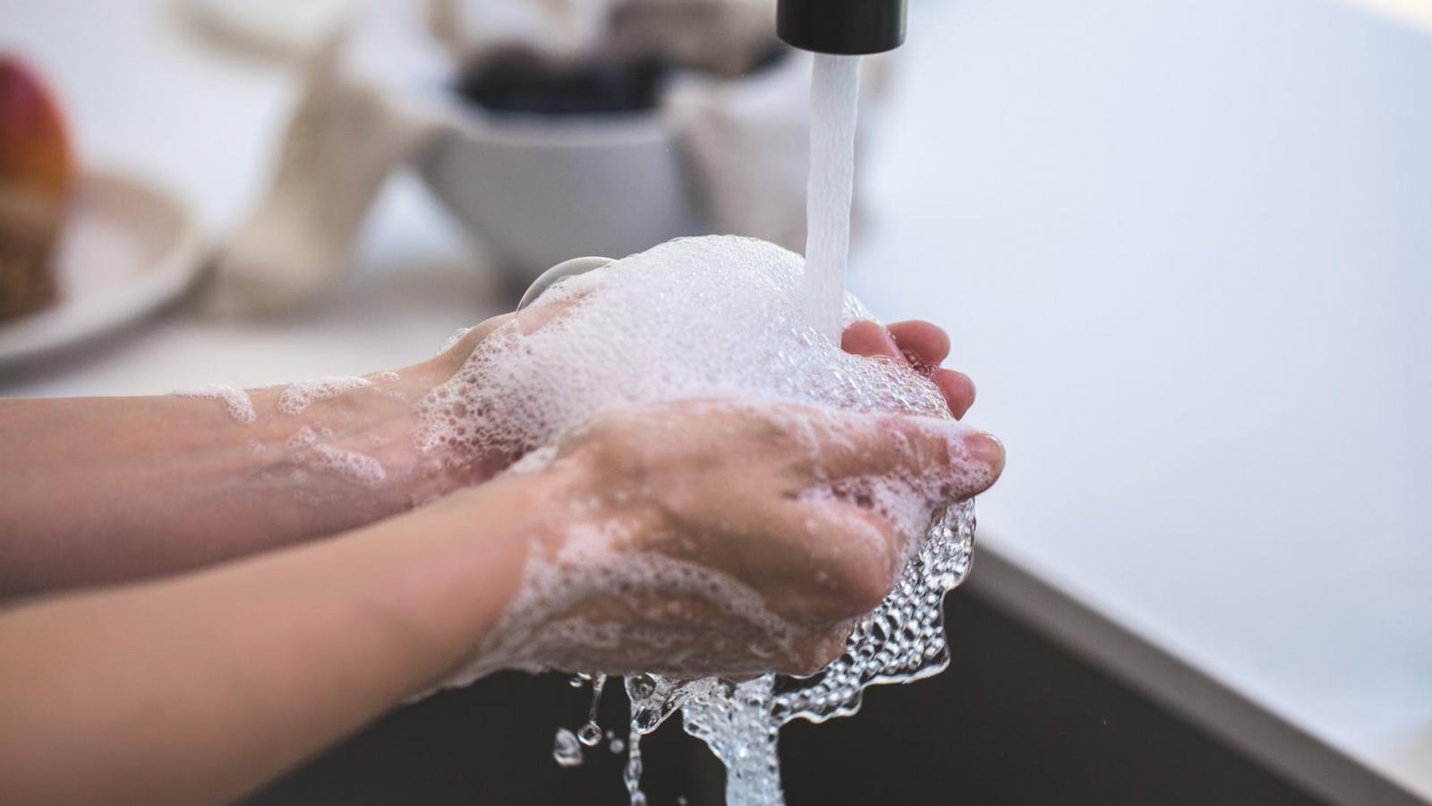 Someone washing hands under a tap